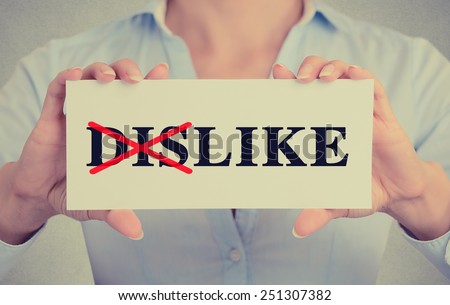 Closeup businesswoman hands holding white card sign with dis crossed in word dislike  text message isolated on grey wall office background. Retro instagram style image