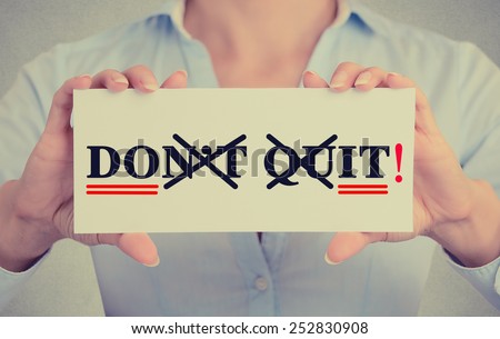 Closeup businesswoman hands holding white card sign with don\'t quit do it text message isolated on grey wall office background. Retro instagram style image