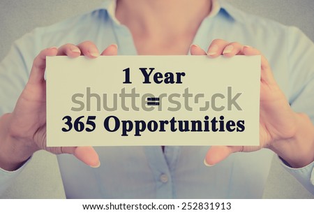 Closeup businesswoman hands holding white card sign with one year 365 opportunities text message isolated on grey wall office background. Retro instagram style image