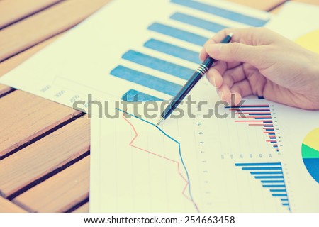 Closeup business woman hands with pen presenting company annual report statement document, papers chart, growing up graph. Stock market, office, tax, education concept.