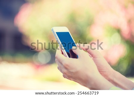 Closeup image woman hands holding, using smart, mobile phone isolated outside city background. New generation technology, people phone addiction concept. Customer, service provider relationship