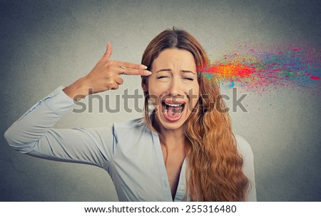 Headshot portrait young woman committing suicide with finger gun gesture, explosion of colors isolated on grey wall background. Human emotions face expressions