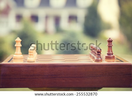 First move over a wood chessboard. Closeup chess game figures isolated outside home background. Real estate sale, home savings, loans market, mortgage plan and residential tax saving strategy concept