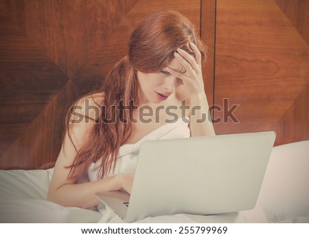 Portrait sad unhappy woman with laptop computer laying in the bed of her bedroom