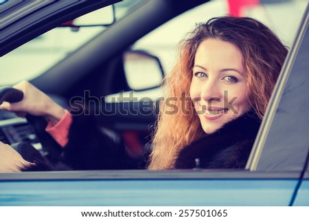 Side portrait smiling attractive happy winter woman, buckled up driving testing her new car, automobile, purchased at dealership isolated street, city traffic background. Safe driving habits concept