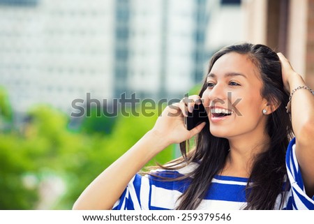 Young happy excited laughing woman talking on mobile phone isolated outdoors city urban background.