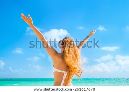 Beautiful woman smiling arms raised up to blue sky celebrating freedom. Positive human emotion feeling life perception success peace of mind vacation concept. Free Happy girl on beach enjoying nature