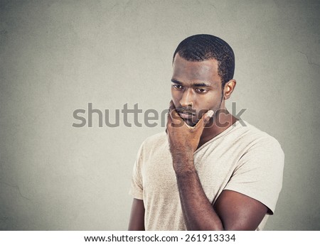 Portrait sad, depressed, worried young man looking down isolated on grey wall background. Human face expressions, emotion, feelings, reaction, life perception