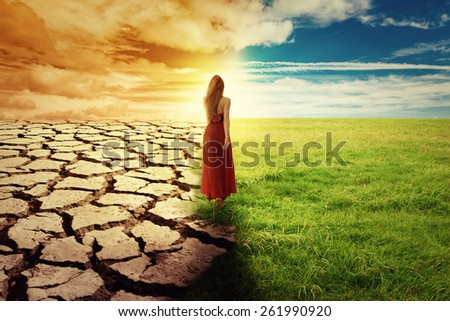A Climate Change Concept Image. Landscape of a green grass and drought land. Woman in green dress walking through an opened field