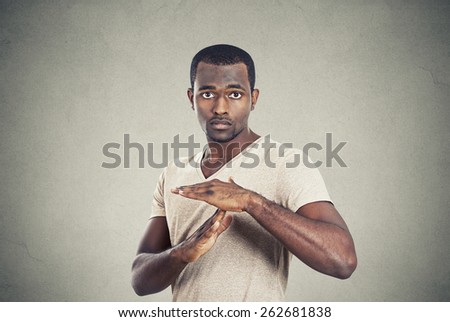 Portrait young confident casual man showing time out gesture with hands isolated grey wall background. Human emotion face expression body language sign symbol