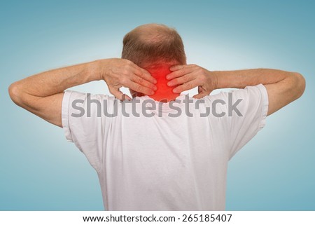 Closeup senior mature man with bad neck spasm pain touching colored in red inflamed area suffering from arthritis isolated on light blue background. Human health problems, geriatrics medicine concept