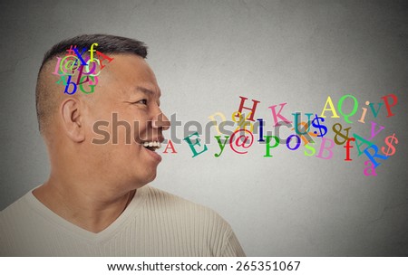 Side view portrait young handsome man talking with alphabet letters coming out of open mouth isolated grey wall background. Human face expression emotion perception. Communication concept