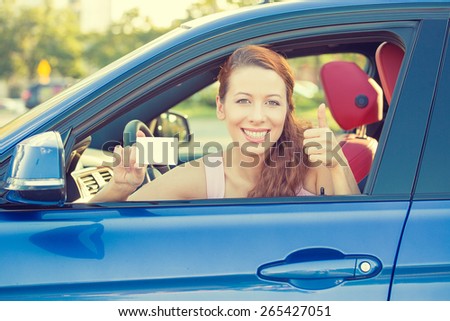Car. Woman driver happy smiling showing thumbs up coming out of car window on summer day