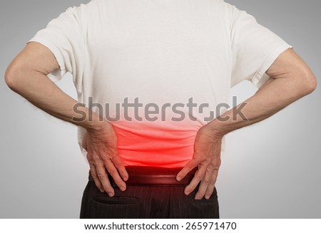 rear view old man grandpa holding his painful lower back colored in red with hands isolated on gray background. Human health problems