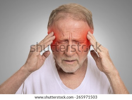 Closeup headshot senior man suffering from headache hands on head with red colored inflamed areas looking down isolated on gray wall background. Human face expression. Health problems issues