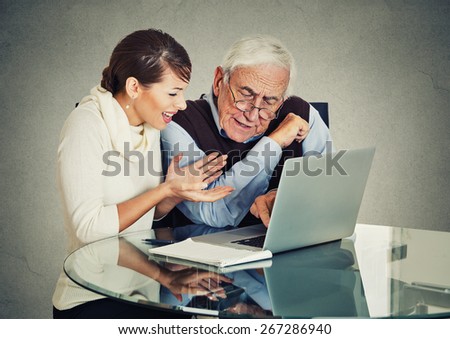 Young woman teaching confused, senior, older, elderly man with eyeglasses how to use laptop. Generation gap differences concept