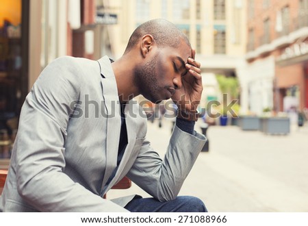 Portrait stressed young man hands on head with bad headache isolated city street background. Negative human emotion facial expression feeling