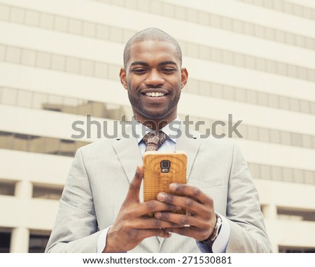 Closeup portrait, happy, cheerful man excited by what he sees on cell phone, isolated outdoor background corporate office. Facial expression, reaction. Businessman sending text message from his mobile