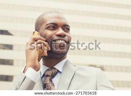 Closeup headshot handsome happy laughing young businessman talking on mobile phone outdoors. Instagram filter effect