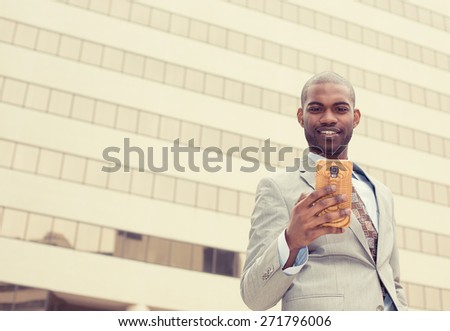 Closeup portrait, happy, cheerful man excited by what he sees on cell phone, isolated outdoor background corporate office. Facial expression, reaction. Businessman sending text message from his mobile