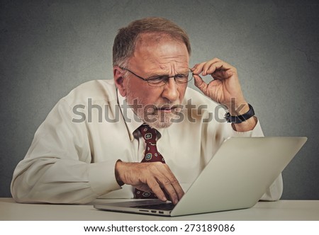 Closeup portrait senior elderly mature business man with glasses having eyesight problems confused with laptop software isolated gray background. Age related changes. technology and senior people