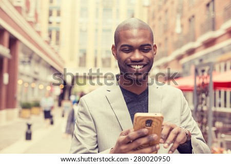 Young happy smiling urban professional man using smart phone. Businessman holding mobile smartphone using app texting sms message wearing jacket