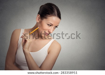 Portrait happy young woman thinking dreaming has ideas looking down isolated grey wall background. Positive human face expression emotion feeling life perception. Decision making process concept.