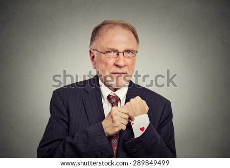 Closeup portrait senior man deal maker pulling out a hidden ace card from the suit jacket sleeve isolated on gray wall background
