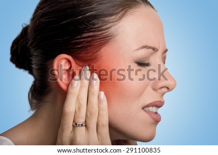 Tinnitus. Closeup up side profile sick female having ear pain touching her painful head isolated on blue background