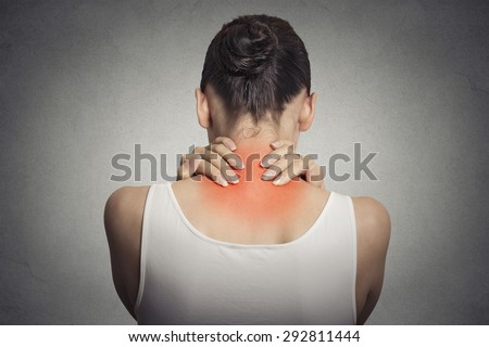 Healthy lifestyle. Back and spine disease. Closeup back view tired female massaging her neck colored in red isolated on gray wall background