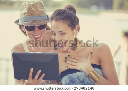 Portrait two funny happy young women friends laughing surprised and sharing social media videos news pictures on mobile pad computer outdoors in park