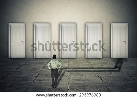 Making a choice opportunity concept. Businessman facing group of career opportunities with his cast shadow preferring or choosing one door entrance symbol for odds of success.