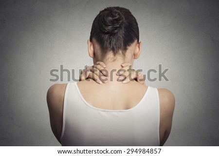 Healthy lifestyle working conditions. Back and spine disease. Closeup back view tired female massaging her painful neck isolated on gray wall background