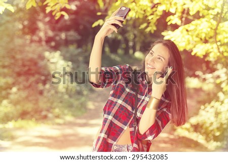 young beautiful woman taking selfie with smart phone in the park