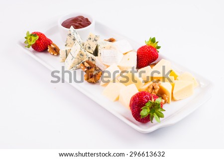 Cheese plate with cheeses Dorblu, Brie, Camembert and Roquefort walnuts, strawberry and jam served on plate table isolated on white background