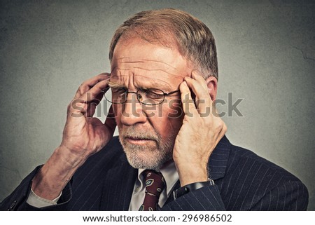 Headshot stressed senior man looking down sad depressed, alone, disappointed, gloomy, hands on head isolated on gray wall background. Human emotion face expression reaction