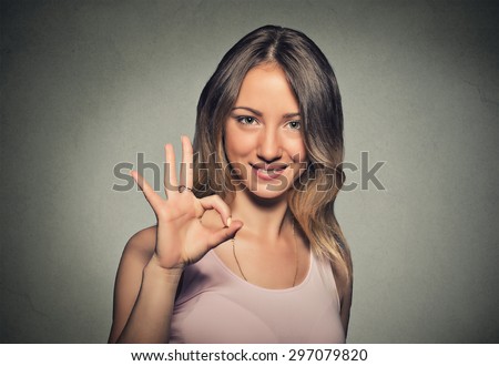 Beautiful happy young woman showing Ok sign isolated on gray wall background. Positive human emotions face expression body language