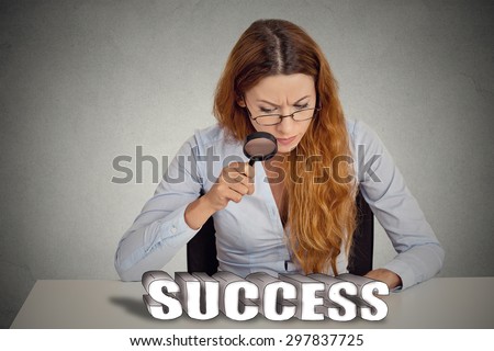 Business woman boss sitting at table looking through magnifying glass at success sign