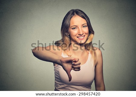 Closeup portrait sarcastic woman showing thumbs down sign hand gesture happy someone made mistake lost failed isolated on grey wall background. Negative emotion feeling attitude