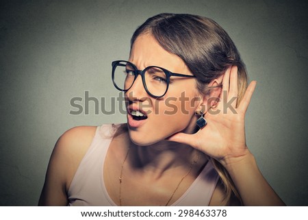 Closeup portrait young nosy woman hand to ear gesture trying carefully intently secretly listen in on juicy gossip conversation news  isolated gray background. Human face expression. Hard to hear