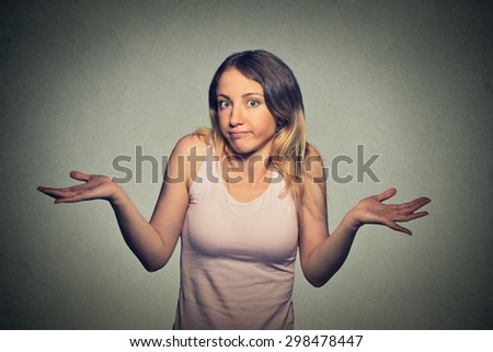 Portrait dumb looking woman arms out shrugs shoulders who cares so what I don\'t know isolated on gray wall background. Negative human emotion, facial expression body language life perception attitude