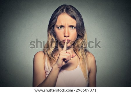 Portrait of beautiful woman with finger on lips isolated on gray background