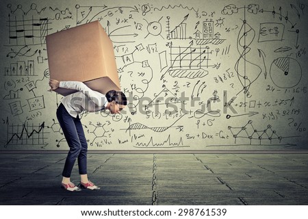 Young woman carrying heavy box walking along gray wall covered with writing of math science life ideas formulas