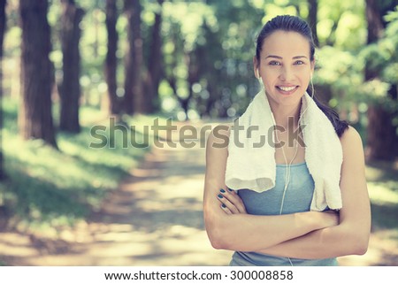 Portrait young attractive smiling fit woman with white towel resting after workout sport exercises outdoors on a background of park trees. Healthy lifestyle well being wellness happiness concept