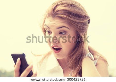 portrait anxious young girl woman looking at phone reading seeing bad news or photos with disgusting emotion on her face isolated outside outdoors background. Human emotion, reaction, expression
