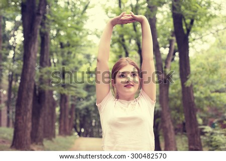Fitness woman stretching exercises on fresh air. Beautiful sportswoman exercising outdoors in park on summer spring day. Young sporty girl doing pilates.