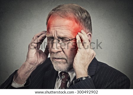 Closeup headshot senior man suffering from headache hands on head with red colored inflamed areas looking down isolated on gray wall background. Human face expression. Health problems issues