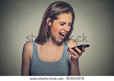 Portrait angry young woman screaming on mobile phone isolated on gray wall background. Negative human emotions feelings