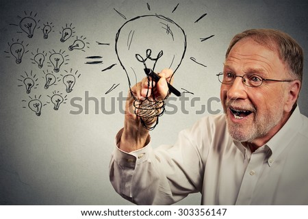 Senior excited businessman has an idea drawing a lightbulb with pen