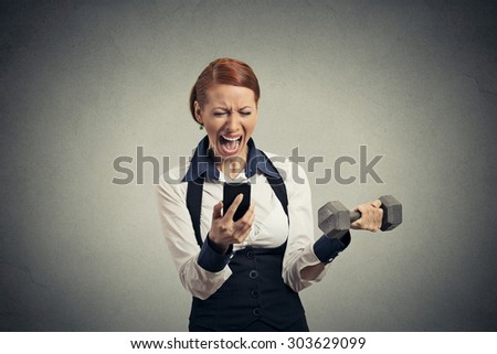 Portrait angry young business woman screaming on mobile phone lifting dumbbell